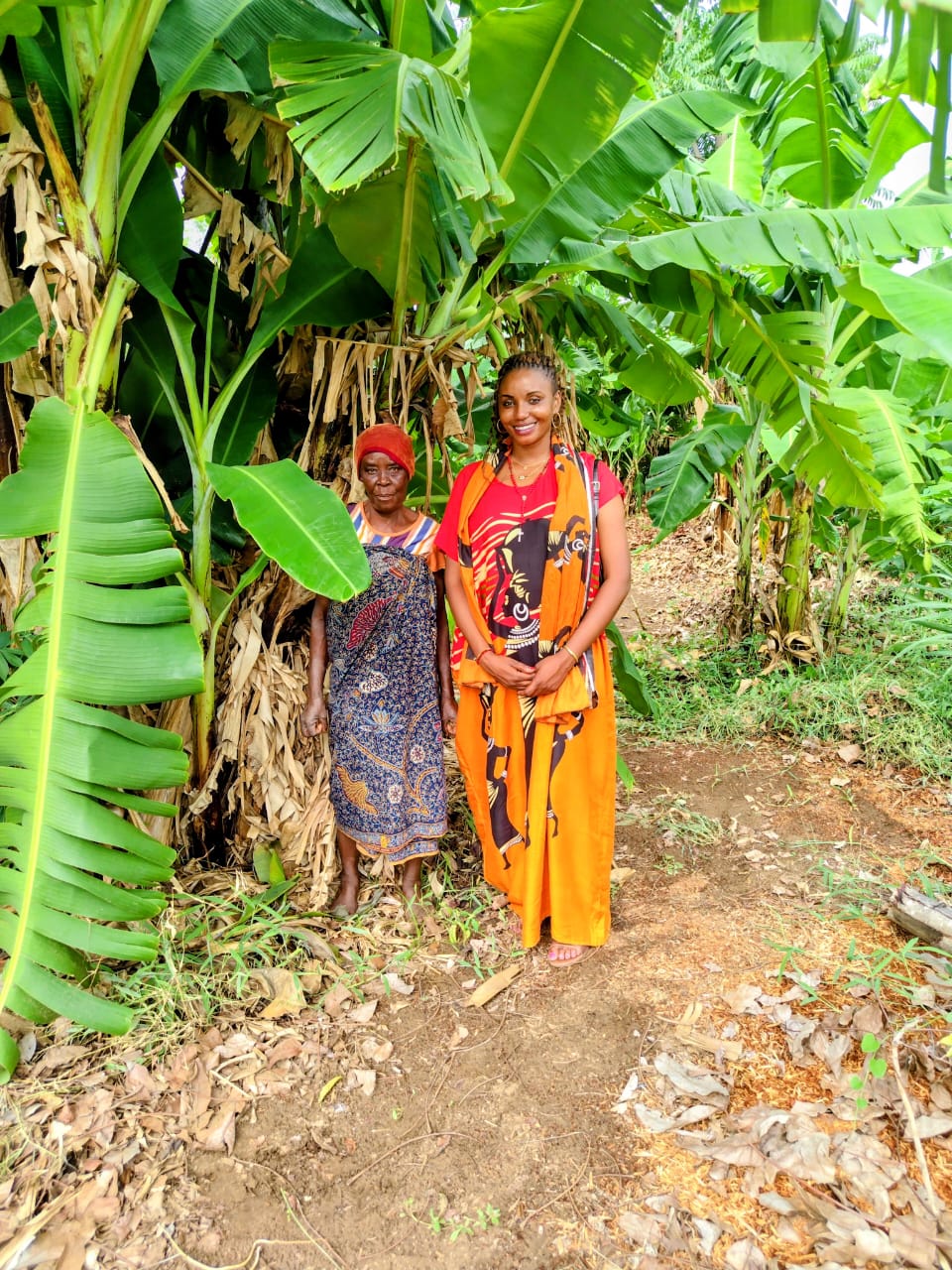 Two women standing among banana trees